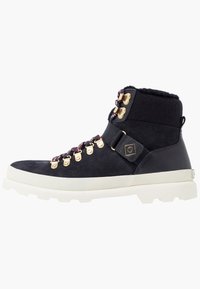 Stivaletto alla caviglia in suede nero con suola in gomma bianca, accessori in oro, lacci colorati e colletto imbottito. Presenta una superficie liscia e un design resistente.