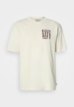 Cream-colored cotton t-shirt with a crew neck. Features a graphic design in purple and green on the left chest area. Short sleeves.