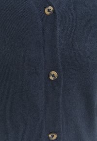 Marinblå stickad cardigan med en strukturerad yta, utrustad med fem runda bruna knappar framtill för stängning.