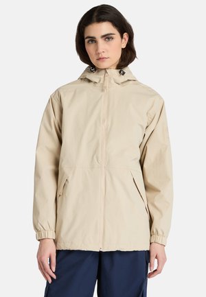 Beige lättviktsjacka med huva, elastiska ärmslut, framdragkedja och sidofickor, tillverkad av slät, vattenavvisande tyg.