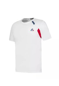 Camiseta de algodón blanca con mangas cortas, que presenta acentos geométricos rojos y azules y un pequeño logotipo en el pecho. Escote redondo.