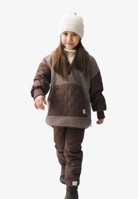 Pullover matelassé marron avec un panneau en polaire et une grande poche frontale, associé à un pantalon matelassé assorti et un bonnet tricoté de couleur claire.