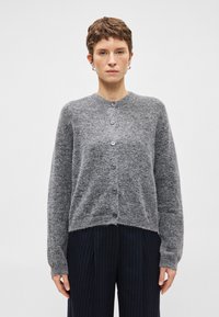 Grijze wollen cardigan met een ronde hals, vijf knopen aan de voorkant en geribbelde manchetten. Zachte textuur met een iets losse pasvorm.