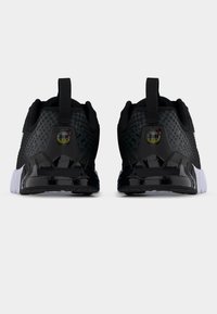 Ζευγάρι αθλητικών παπουτσιών σε ασπρόμαυρο, προβεβλημένα από πίσω, με υφαντές διχτυωτές επιφάνειες και θηλιές στο πίσω μέρος με εμφανή λογότυπα Air Max.