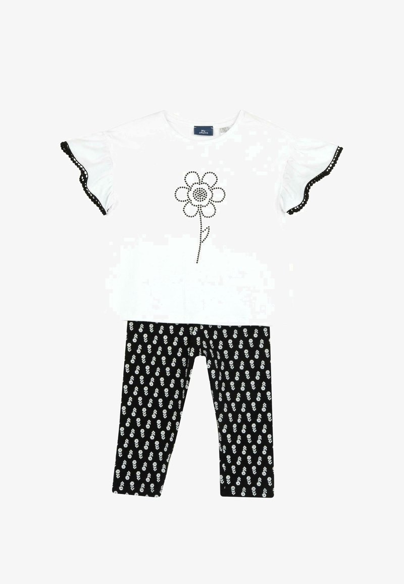 Haut court à manches courtes blanc avec des bordures noires et un motif floral, associé à un legging noir à motif floral blanc.
