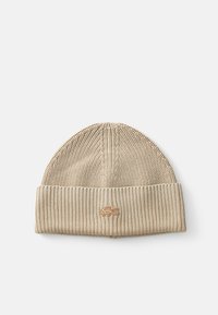 Gorro de punto beige con textura acanalada, que presenta un logo de Lacoste en marrón claro cosido en el puño doblado.