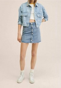 Jeansjacka med framfickor, ljusblå färg och silverfärgade knappar. Matcher med en ljusblå jeanskjol med framknappar och fransad fåll.