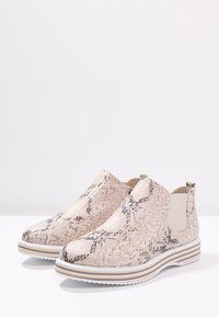Stivali alla caviglia beige con stampa a serpente, dalla texture liscia, con pannelli laterali elasticizzati e suola a righe bianca e beige.