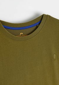 Oliwkowa koszulka z okrągłym dekoltem z niebieskim akcentem na linii szyi, z małym haftowanym logo na lewej piersi. Gładka bawełniana tkanina.