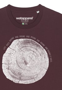 Bordeauxrotes T-Shirt mit einem runden Baumstumpf-Grafik und dem Text "DAS LEBEN GEHT RUNDER UND RUNDER" in Weiß. Hergestellt aus Bio-Baumwolle, mit Rundhalsausschnitt.
