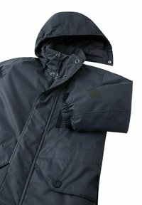 Ciemnoszara ocieplana kurtka z kapturem, zamykanymi na zamek kieszeniami, elastycznymi mankietami i zatrzaskami. Materiał ma gładką, wodoodporną teksturę.