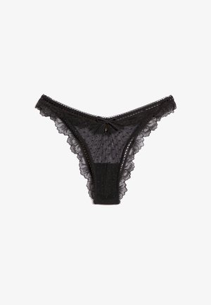 Schwarzer transparenter Spitzentanga mit Pünktchenmuster, gewellten Rändern und kleinem Schleifendetail in der vorderen Mitte.