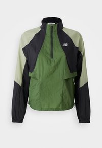 Veste légère verte et noire avec un zip quart, des poignets élastiques, deux poches avant et des panneaux contrastants en tissu texturé.