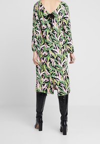 Floral midi dress in pink, green, and black; features a V-back with a black bow, long sleeves, and a loose fit design. Pairing with knee-high boots.