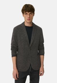 Dunkelgrauer Blazer aus strukturiertem Strickstoff mit einem Ein-Knopf-Verschluss, Reverskragen und zwei Fronttaschen. Lange Ärmel mit kontrastierenden Manschetten.