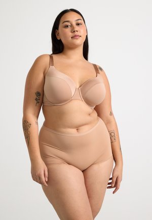 Soutien-gorge beige avec coques moulées et bretelles ajustables, associé à des culottes taille haute assorties, toutes deux en tissu lisse et extensible.
