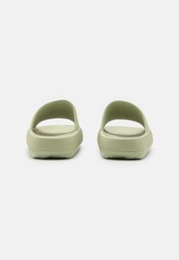 Sandale verzi tip slip-on cu o curea texturată și talpă netedă, având un design deschis la spate pentru respirabilitate și confort.