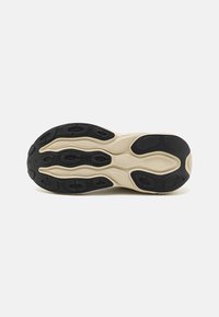 Semelle de chaussure avec base crème et motifs en caoutchouc noir conçus pour la traction et le soutien, présentée sur un fond blanc uni.