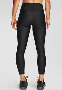 Czarne legginsy z wysokim stanem wykonane z elastycznego materiału. Charakteryzują się gładką fakturą, dopasowanym krojem i kontrastującym przeszyciem wzdłuż szwów.