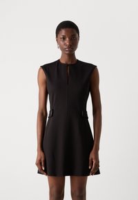 Black sleeveless dress with a high neckline, front keyhole detail, and side accents. Made from smooth, structured fabric, knee-length.