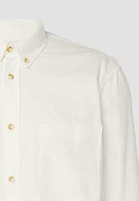 Biała koszula z guzikami z przodu, z kieszenią na piersi i beżowymi guzikami, zapięta pod kołnierzykiem, widoczna od klatki piersiowej w górę.