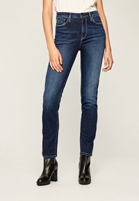 Mörkblå denimjeans med slim fit, hög midja och klassisk femficksdesign, i kombination med svarta läderankelboots.