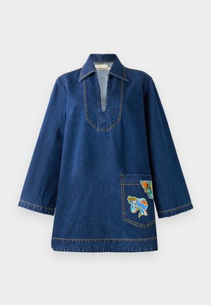 Denim-tunika med djup V-ringning, långa ärmar, kontrasterande gula sömmar och en broderad ficka med färgglada mönster.