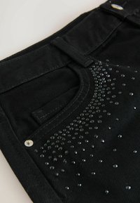 Sorte denim jeans med krystaludsmykninger på lommen foran. Har et klassisk design, metalhardware og et struktureret stof.