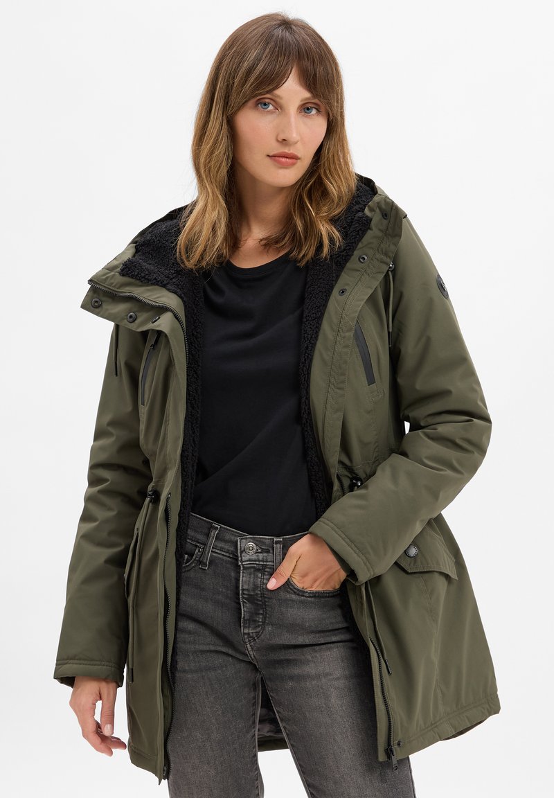 Parka imbottito verde oliva con colletto foderato in fleece nero, chiusure a cerniera e a bottone, vita regolabile con coulisse e numerose tasche.