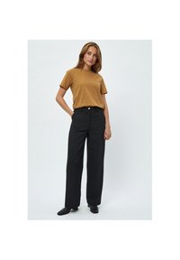 Brun t-shirt med kort ärm som kombineras med högmidjade svarta byxor. Byxorna har rak passform och knappstängning, vilket skapar en minimalistisk look.