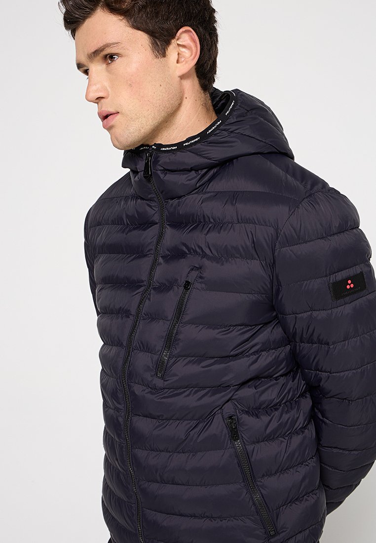 Giacca puffer blu navy con cappuccio, caratterizzata da un design a righe orizzontali, tasche laterali con zip e dettagli sul colletto con logo. Tessuto liscio con una sensazione di leggerezza.