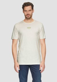 Jasno beżowa koszulka z krótkim rękawem, okrągły dekolt, wykonana z bawełny, z małym zielonym logo s.Oliver na piersi. Gładka tekstura, casualowy krój.