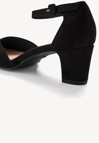 Chaussure à talon haut en suede noir avec un bout arrondi et une bride de cheville, dotée d'un talon court et solide et d'une doublure intérieure lisse.