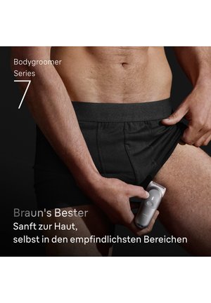 Mann in schwarzer Unterwäsche benutzt einen elektrischen Körperrasierer am oberen Oberschenkel und hebt dabei die sanfte Rasur für empfindliche Bereiche hervor.