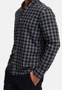 Koszula w czarno-szarą kratę zapinana na guziki, z długimi rękawami, wykonana z bawełny, z drewnianymi guzikami, zaostrzonym kołnierzykiem i klasycznym krojem.