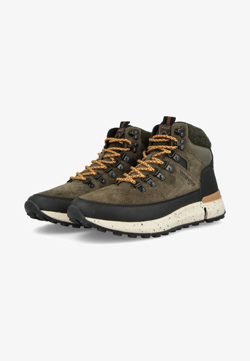 Paire de bottes de randonnée montantes vert olive et noires avec des lacets orange et des semelles blanches mouchetées, de marque "Wrangler" sur le côté.