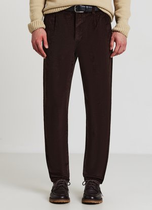Braune Cordhosen mit geradem Schnitt, die über eine subtile Textur und einen Bund verfügen. Kombiniert mit dunklen Schnürschuhen.