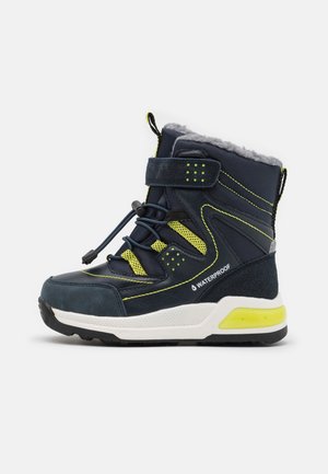 Botte d'hiver imperméable bleu marine et jaune fluo pour enfants, avec fermeture à lacets, sangle à velcro, doublure en fourrure et semelle blanche épaisse.