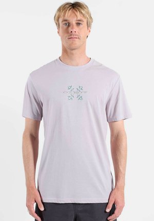 T-shirt en coton violet clair à manches courtes et col rond. Présente un motif central avec des accents de feuilles vertes et bleues.