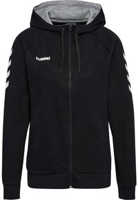 Sweat à capuche noir zippé avec une doublure intérieure grise, présentant des motifs chevrons blancs sur les manches et une capuche à cordon de serrage. Logo "Hummel" sur la poitrine.