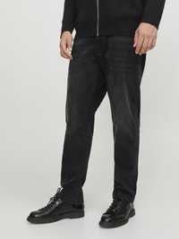 Jeans de mezclilla negros con un corte relajado, que presentan una textura ligeramente descolorida. Combinados con botas negras con cordones para un look monocromático.