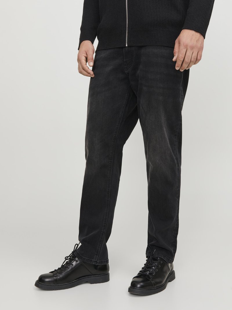 Jeans de mezclilla negros con un corte relajado, que presentan una textura ligeramente descolorida. Combinados con botas negras con cordones para un look monocromático.