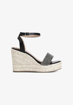 Černé wedges sandály s tkanou provázkovou podrážkou a lesklým stříbrným páskem. Mají nastavitelné popruhy kolem kotníku a hladký kožený povrch.