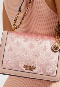 Borsa a tracolla rosa con finitura satinata texture, motivo in rilievo, hardware color oro e tracolla a catena. Logo del marchio in mostra.