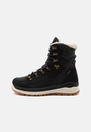 Stivale invernale nero con fodera in pile, occhielli metallici, suola spessa scolpita e design alla caviglia per uso esterno e tempo freddo.