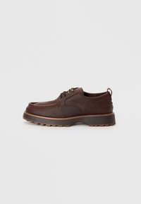 Pantofi din piele maro cu o finisare texturată, talpă rezistentă cu un profil bine definit și vârf rotund. Prezintă ochiuri metalice și o talpă intermediară maro în contrast.