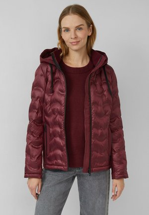 Burgundy puffer jacket with a hood, featuring a quilted design, side pockets, and black accents. Worn over a matching sweater.