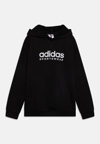 Musta pehmeästä kankaasta valmistettu huppari, jossa on etutasku, resorit hihansuissa ja valkoinen "adidas SPORTSWEAR" -logo rinnassa.