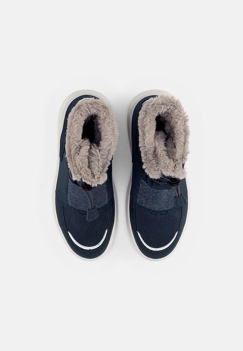 Chaussures bleu marine avec une douce doublure en fausse fourrure beige, fermeture élastique et un panneau en toile texturée. Comprend une semelle en caoutchouc blanche.