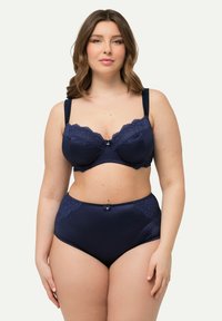 Navy blue-langebåset som har en bh med blonderkant og en sløyfe, samt høyt midje truser med blonderdetaljer, begge med både tekstur og glatte overflater.
